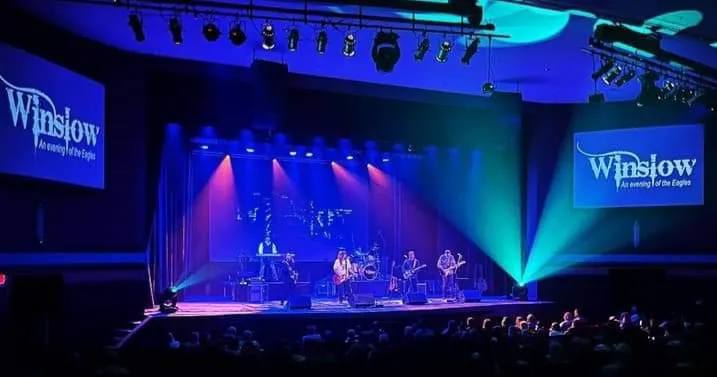 Winslow performing at large venue with teal screens