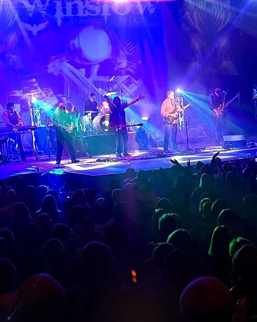 Winslow on stage — crowd hands up, blue lights